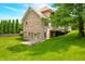 Lush backyard featuring a brick house with well-maintained lawn, mature trees, and deck area at 1008 Westcreek Dr, Columbus, IN 47201