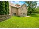 Lush backyard featuring a brick house with well-maintained lawn, mature trees, and patio area at 1008 Westcreek Dr, Columbus, IN 47201
