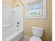 Bathroom featuring a toilet next to a shower-tub combination with a large window at 1008 Westcreek Dr, Columbus, IN 47201
