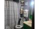Quaint bathroom featuring green vanity, decorative shelves, and a colorful shower curtain for a cheerful ambiance at 10210 E 33Rd St, Indianapolis, IN 46235