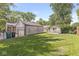Large backyard featuring lush green grass, a detached garage, a shed, and partial fencing at 1205 Park Dr, Lebanon, IN 46052