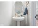 Compact powder room featuring pedestal sink, round mirror, and modern decor at 12078 Black Mill Pass, Fishers, IN 46040