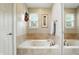Bright bathroom featuring a soaking tub with beige tile surround and framed art at 13020 Lombard Ct, Fishers, IN 46038