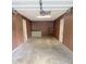 View of the garage featuring bare floors, wooden walls, storage area, and interior lighting at 1306 Woodbine Dr, Anderson, IN 46011