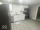 Modern kitchen featuring stainless steel appliances, white cabinets, tile backsplash, and gray vinyl flooring at 1306 Woodbine Dr, Anderson, IN 46011
