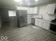 Modern kitchen featuring stainless steel appliances, white cabinets, and attractive gray vinyl flooring at 1306 Woodbine Dr, Anderson, IN 46011
