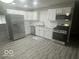 Modern kitchen featuring stainless steel appliances, white cabinets, and attractive gray vinyl flooring at 1306 Woodbine Dr, Anderson, IN 46011