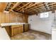 Unfinished basement area with exposed ceiling, wood paneled wall, and a sink with cabinet at 1310 S Catherwood Ave, Indianapolis, IN 46203
