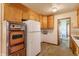 Traditional kitchen featuring wooden cabinets, a white refrigerator, and access to the bathroom at 1310 S Catherwood Ave, Indianapolis, IN 46203