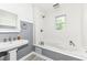 Bright bathroom with a white pedestal sink and a soaking tub with gray wainscoting at 1325 Fordice Rd, Lebanon, IN 46052
