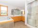 Bright bathroom featuring a large soaking tub, natural wood trim around the window, and glass shower stall at 1595 N 400 W, Greenfield, IN 46140