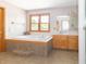 Bright bathroom showcasing a large soaking tub and natural wood trim around the vanity and window at 1595 N 400 W, Greenfield, IN 46140