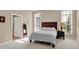 Bright bedroom featuring neutral walls, carpet, and a bed with wooden headboard, bedside table, and two windows at 1631 Caspian Dr, Carmel, IN 46032