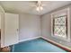 Small bedroom with window, ceiling fan and carpet over hardwood floors at 1908 W Northgate St, Indianapolis, IN 46228