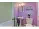 Charming powder room features lilac walls, a pedestal sink, and decorative floral accents at 238 S 5Th Ave, Beech Grove, IN 46107