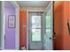 Hallway offers a glimpse to the exterior through a glass paneled door and colorful adjacent rooms at 238 S 5Th Ave, Beech Grove, IN 46107