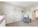 Neutral toned bedroom with cozy chair, two closets, and doorway to the hallway at 301 Cobblesprings Ct, Avon, IN 46123