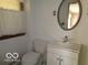 Bathroom featuring a white vanity, toilet, and a round mirror at 3253 W 34Th St, Indianapolis, IN 46222