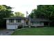 Charming two-story home with stone accents, green shutters, and an attached garage nestled among lush greenery at 3253 W 34Th St, Indianapolis, IN 46222