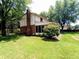 A lovely shot of the home's rear exterior with a brick chimney, a charming sunroom, and a well-manicured lawn surrounded by mature trees at 336 N Windsong Ln, Greenwood, IN 46142