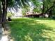 A spacious backyard with mature trees, a large lawn, and a home featuring a covered porch, perfect for enjoying the outdoors at 336 N Windsong Ln, Greenwood, IN 46142