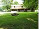 Backyard featuring a home with a covered porch, mature trees, ample lawn space, and a cozy fire pit area for outdoor gatherings at 336 N Windsong Ln, Greenwood, IN 46142