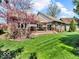 Backyard of brick home with wooden deck and vibrant flowering tree adding color to the landscape at 3559 Towne Dr, Carmel, IN 46032