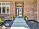 Close-up of the home's entrance showcasing brickwork, a decorative door, and flower planters at 3559 Towne Dr, Carmel, IN 46032