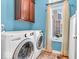 Bright laundry room with blue walls, wooden cabinets, and modern LG washer and dryer at 3559 Towne Dr, Carmel, IN 46032