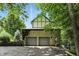 Stone clad detached garage with two bays and a driveway, framed by mature trees and landscaping at 380 Raintree Dr, Zionsville, IN 46077