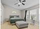 Light-filled main bedroom with a ceiling fan, large window, bedside table and plush ottoman at 3843 Grove Tree Ln, Indianapolis, IN 46203