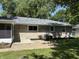 Exterior view of the home's rear with a patio and a well-maintained lawn surrounded by lush trees at 3906 N Lanewood Dr, Muncie, IN 47304