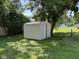 Backyard shed with a door, surrounded by a grassy lawn and mature trees providing shade and privacy at 3906 N Lanewood Dr, Muncie, IN 47304