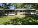 Exterior view of the home's rear with a patio and a screened in porch overlooking a well-maintained lawn at 3906 N Lanewood Dr, Muncie, IN 47304
