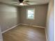 This bedroom features wood-look flooring, a ceiling fan, and a bright window at 3906 N Lanewood Dr, Muncie, IN 47304