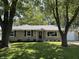 Charming home with manicured lawn, stone facade, and mature trees providing shade and curb appeal at 3906 N Lanewood Dr, Muncie, IN 47304