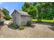 A small wooden shed in a backyard setting with gravel, landscaping and mature trees at 45 Kirk E Dr, Indianapolis, IN 46234