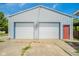 Large detached garage with two white doors, a red side door, and a concrete apron at 4644 E 150 N, Anderson, IN 46012