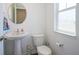 Cozy half bathroom featuring a pedestal sink, toilet, window with privacy glass, and neutral decor at 507 Redvine Dr, Sheridan, IN 46069