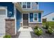 Inviting front entry with a modern door, stylish lighting, brick accents, and manicured landscaping at 507 Redvine Dr, Sheridan, IN 46069