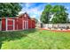 Beautiful backyard with a storage barn, red barn, green grass and patio space at 5821 Pemberly Dr, Indianapolis, IN 46221