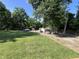 Expansive backyard featuring green lawn, outbuildings, mature trees, and parking, a rural paradise at 6238 E Southport Rd, Indianapolis, IN 46237