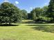 This is a sprawling green backyard with mature trees and a serene pond, perfect for nature lovers at 6238 E Southport Rd, Indianapolis, IN 46237