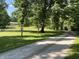 Long driveway winding through a lush, tree-filled lawn leading up to a charming home at 6238 E Southport Rd, Indianapolis, IN 46237