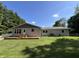Rear exterior view featuring a wooden deck, fenced-in yard, and mature landscaping, an ideal spot for outdoor enjoyment at 6238 E Southport Rd, Indianapolis, IN 46237