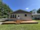 Back of house with a small deck, large windows, nice trim work, and beautiful green trees around it at 6238 E Southport Rd, Indianapolis, IN 46237