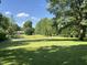 Expansive front yard featuring a vibrant green lawn, mature trees, and a home in the background at 6238 E Southport Rd, Indianapolis, IN 46237