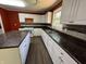 Galley kitchen featuring white cabinetry, dark countertops, stainless sink, and modern appliances at 6238 E Southport Rd, Indianapolis, IN 46237