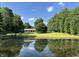 Picturesque view of a tranquil pond reflecting the sky, surrounded by lush greenery and a charming home at 6238 E Southport Rd, Indianapolis, IN 46237