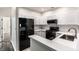 Kitchen with black appliances, white cabinets and view of hallway with carpet flooring at 6592 Reserve Dr, Indianapolis, IN 46220